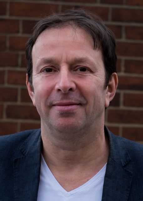 Portrait in a navy blazer and white T-shirt, brick wall